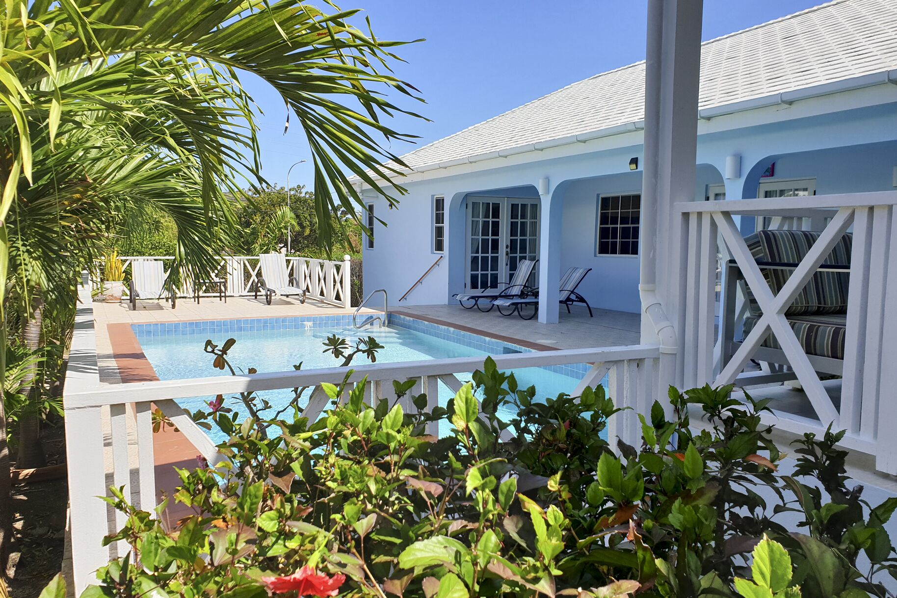 A poolside area with a pool, lounge chairs, and a covered seating area.