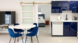 Een moderne hotelkamer met een eethoek, een keuken en een slaapkamer.