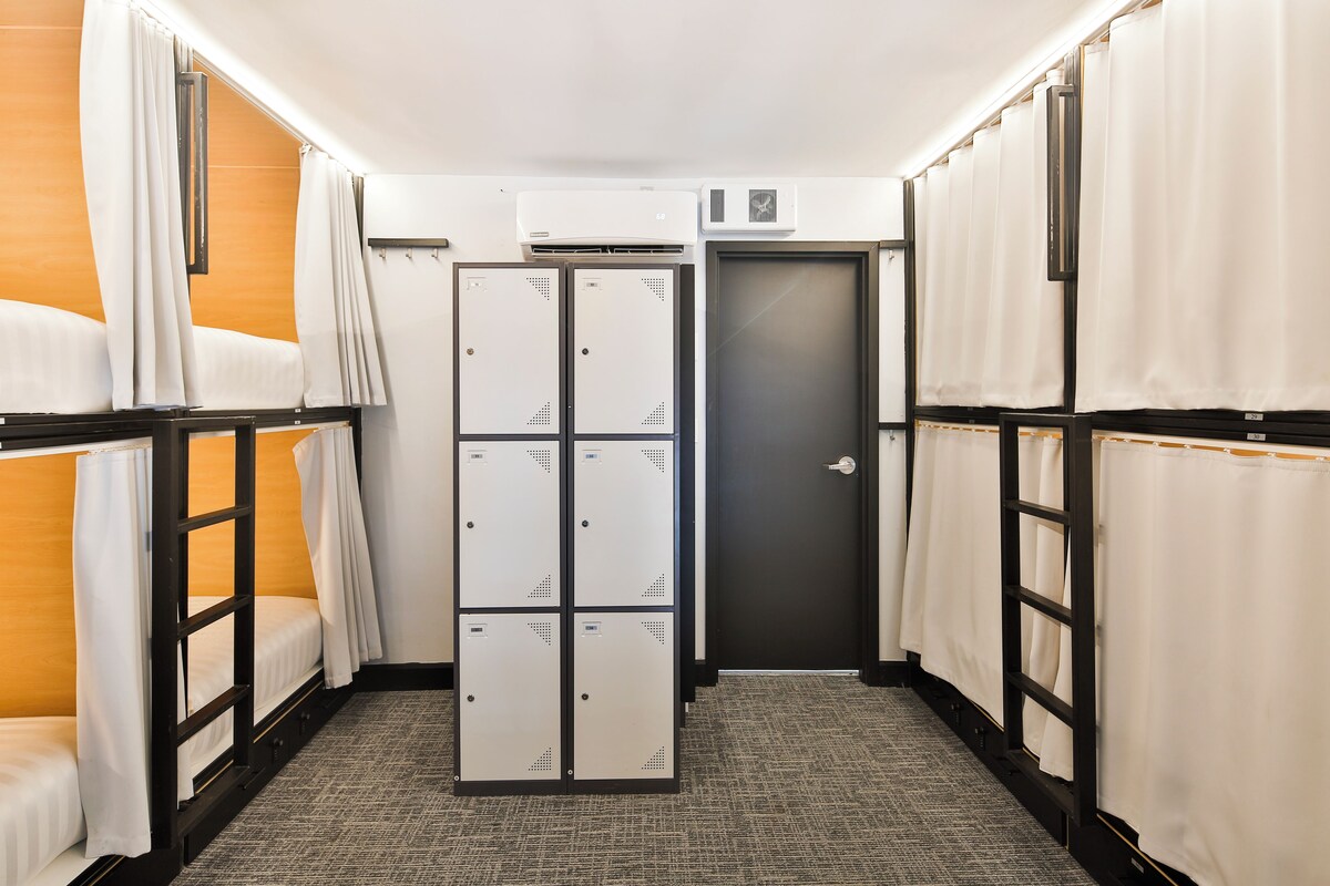A hotel corridor with bunk beds, a door, and lockers.