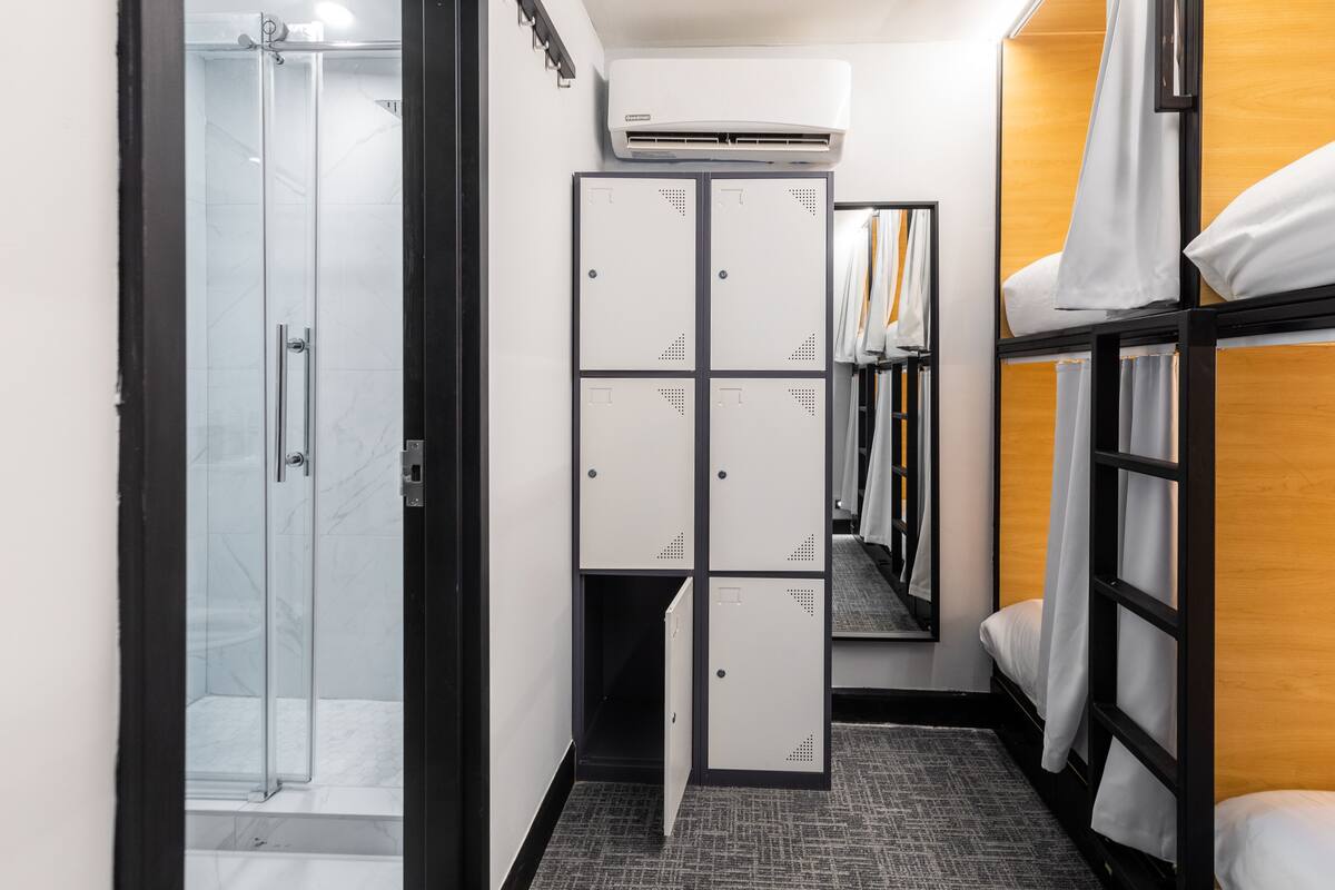 Une chambre d’hôtel avec une douche, une armoire et un lit doté de rideaux.