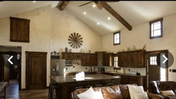 A spacious living area with a large brown leather sofa, wooden cabinets, and a central island with a sink. - Experience the West Texas Rockies (Guthrie)