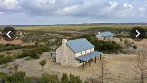 A stone house with a blue roof, surrounded by sparse vegetation and a flat landscape. - Experience the West Texas Rockies (Guthrie)