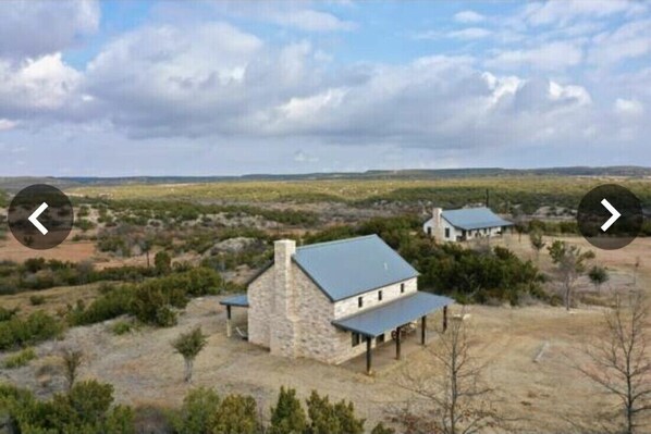 A stone house with a blue roof, surrounded by sparse vegetation and a flat landscape. - Experience the West Texas Rockies (Guthrie)