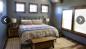 A bedroom with a bed, two bedside tables, a window, and a wooden bench. - Experience the West Texas Rockies (Guthrie)