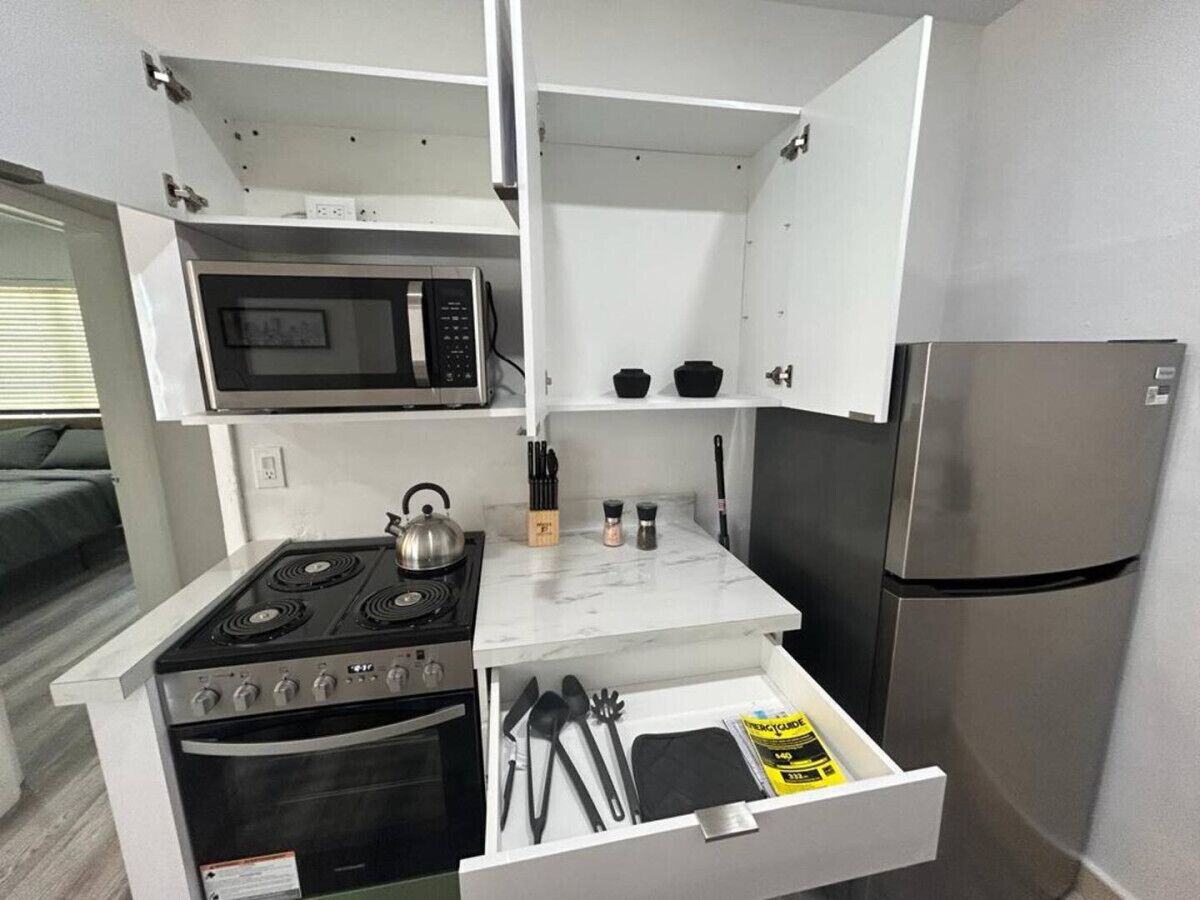 Una cocina compacta con estufa, microondas y refrigerador.