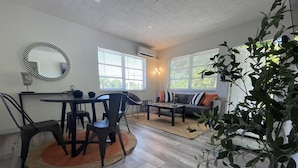 A dining area with a round table, chairs, and a rug. There is a sofa with pillows in the background. - 2655 SW - APT 3 · Great Apart near CocoWalk & Brickell w/parking! (Miami)