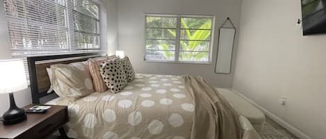 Un dormitorio con cama, mesita de noche, lámpara y ventana con persianas.