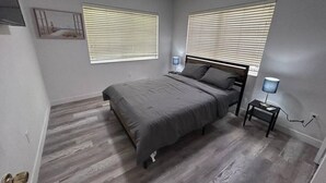 Un dormitorio con una cama, dos mesitas de noche y una lámpara de pared.