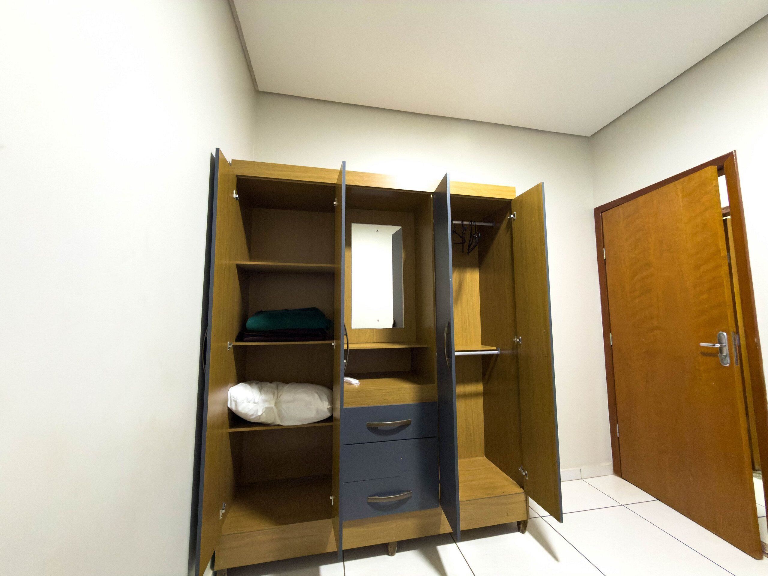 Un dressing avec des portes ouvertes, des étagères et des tiroirs.