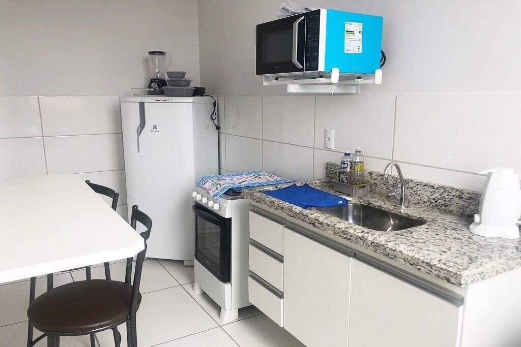 Cocina compacta con refrigerador, microondas, estufa y pileta.