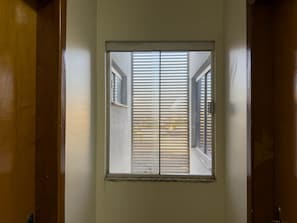 Una ventana con persianas horizontales, un marco de puerta y una ventana más pequeña encima.