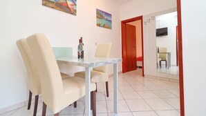 A dining area with a marble table and two beige chairs.
