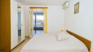 Quarto com uma cama grande, um guarda-roupa e uma varanda com uma cadeira.