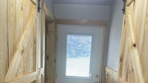 A narrow hallway with wooden walls and a door at the end. - The Stillhouse Cabin, mins from Red River Gorge (Campton)