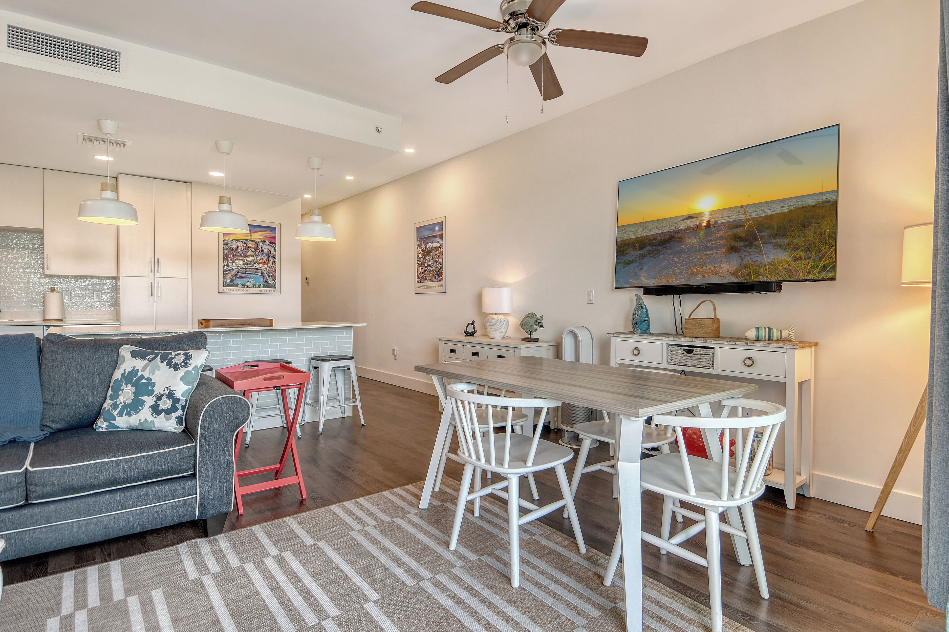 A modern living space with a dining area, kitchen, and a ceiling fan.