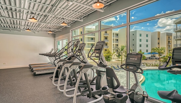 A gym with treadmills and exercise bikes, large windows, and a pool area. - Charming Waterfront 1/1.5 Beautiful Sunsets at the Strand! (Sarasota)