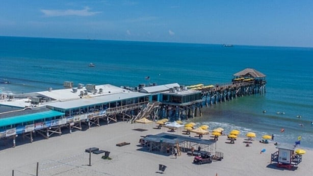 Un muelle en la playa con un restaurante y sombrillas.