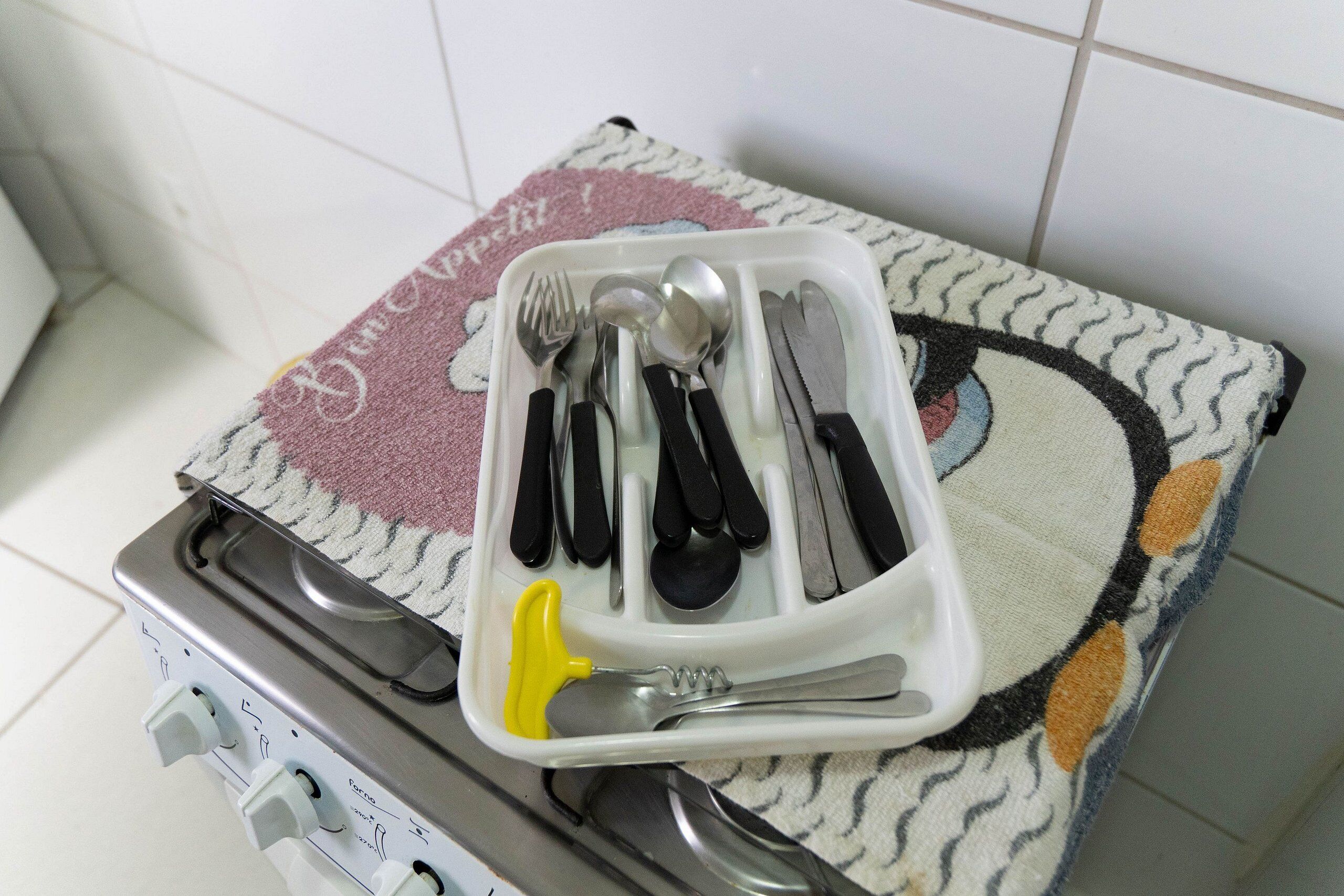Una cocina con una bandeja de utensilios sobre un tapete, una estufa y un enchufe.
