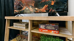 Un téléviseur diffusant un paysage montagneux, une étagère en bois avec des jeux de société et un vélo.