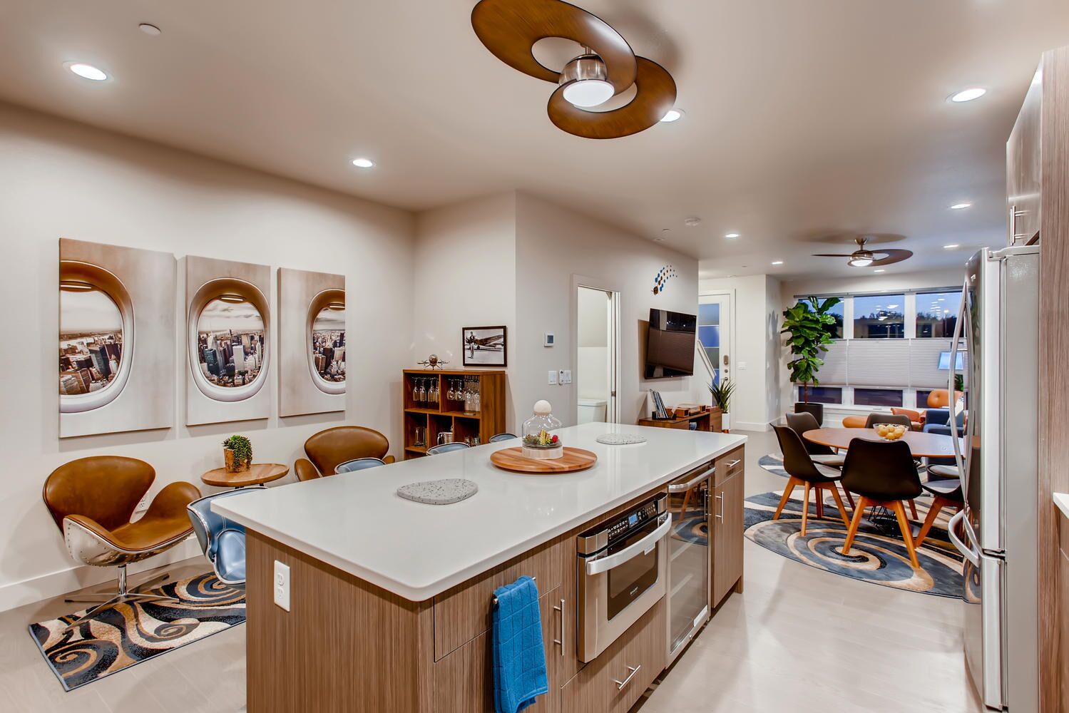 A modern kitchen with a central island, wooden cabinetry, and a built-in oven.