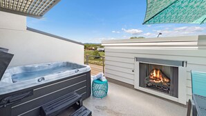 Un bain à remous et une cheminée sur une terrasse extérieure offrant une vue dégagée sur le paysage environnant.