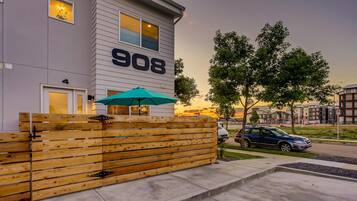 Un bâtiment moderne avec le numéro 908 sur la façade, une clôture en bois et une voiture garée.