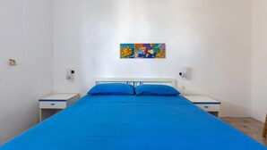 A bedroom with a large bed, two bedside tables, a wall-mounted painting, and a white headboard. - 3137 Villetta Velia by Barbarhouse (Porto Cesareo)