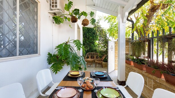 A dining area with a table set for four, surrounded by white chairs, with a view of greenery and a wooden pergola. - 3137 Villetta Velia by Barbarhouse (Porto Cesareo)