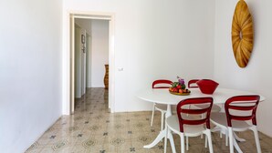 A dining area with a white table and red chairs, a fruit bowl, and a wall-mounted decorative piece. - 3137 Villetta Velia by Barbarhouse (Porto Cesareo)