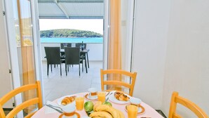A breakfast table with croissants, bananas, and juice, overlooking a scenic view of the sea. - Apartments Ane (Konavle)
