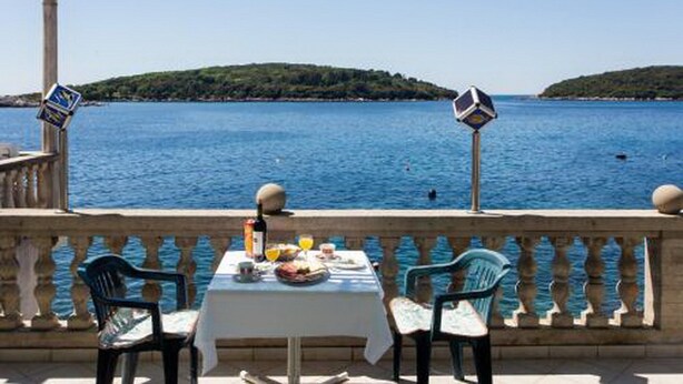 A table set with food and drinks, overlooking a body of water with a distant island. - Apartments Ane (Konavle)