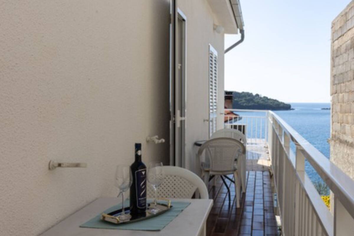 A balcony with a table, chairs, a bottle, and a glass.