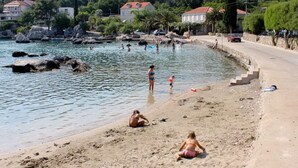 A coastal beach with people, a sandy shore, and buildings in the background. - Apartments Ane (Konavle)