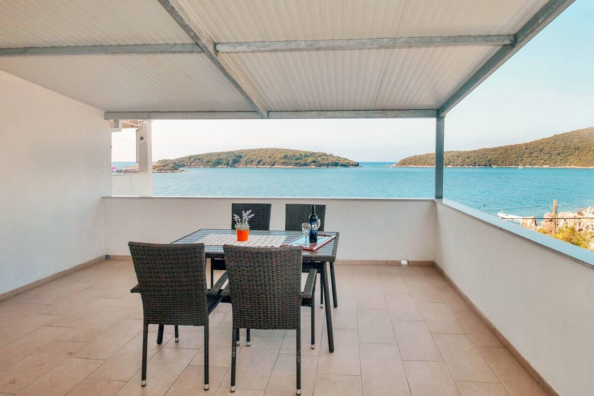 A covered outdoor dining area with a view of the sea and a distant island.