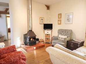 A cozy living room with a wood-burning stove, comfortable seating, a television, and framed artwork on the wall.
