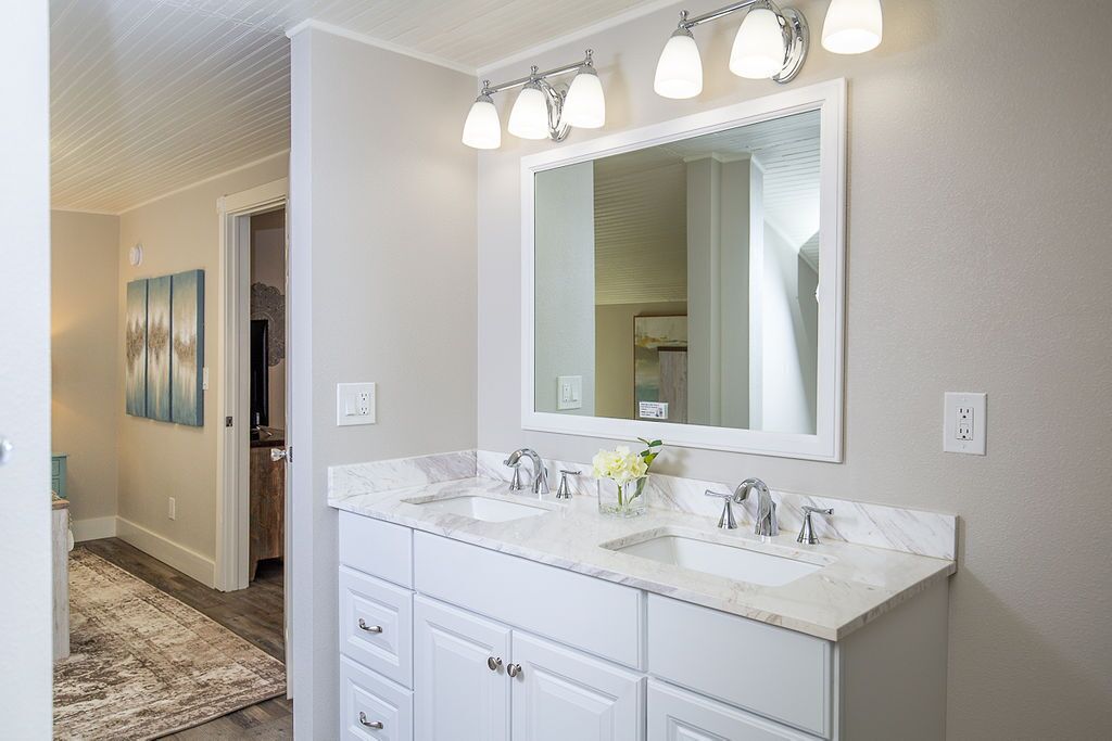 A bathroom with two sinks, a large mirror, and a light fixture above the mirror.