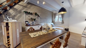 Un soggiorno moderno con parete in mattoni, tavolo da pranzo in legno, divano bianco e lampada a sospensione.