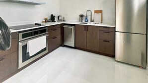 Eine moderne Küche mit Edelstahlgeräten, Holzschränken und einem weiß gefliesten Boden.
