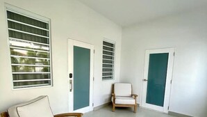 Ein geräumiges Zimmer mit großem Fenster, einer Tür und einem Stuhl.