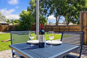 A table with two chairs, a bottle of wine, and two glasses on a blue tablecloth.