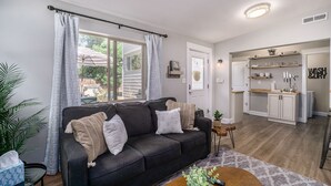 Un salon avec un canapé foncé, une table basse et une vue sur la cuisine.