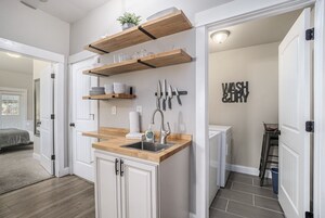 Cocina compacta con estantes de madera, un lavabo y un letrero que dice 'WASH & DRY'.