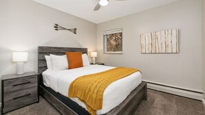 A bedroom with a bed, nightstands, a ceiling fan, and wall art. - Butterscotch Suite Old Town Stay with Sunny Style (Fort Collins)