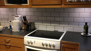 Une cuisine avec des meubles en bois, un four à micro-ondes, une cuisinière et une machine à café.