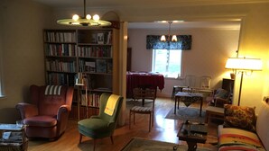 Un salon comprenant une bibliothèque, un coin repas, un canapé et une lampe.