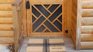 A wooden cabin entrance with a glass door, a welcome mat, and a lantern. - Shenandoah National Park - Sauna - Log Cabin - Treehouse - Game Room (Stanley)
