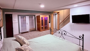 Ein Schlafzimmer mit einem Bett, einem Holzschrank, einem Fernseher und einer Treppe.