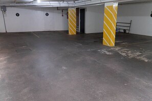 An underground parking area with concrete flooring and yellow-striped pillars. - CONDOMÍNIO SONHARE - 204 (Anapolis)