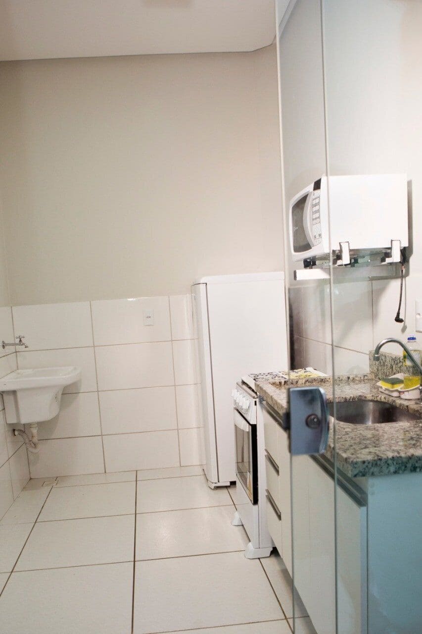 Une cuisine avec des meubles blancs, un four à micro-ondes encastré, un évier et une cuisinière.