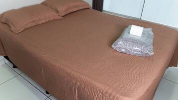 Una cama individual con una cubierta marrón y una bolsa plástica encima.